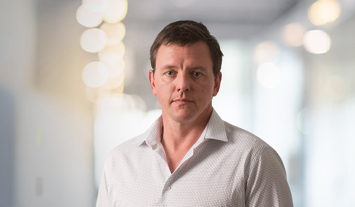 Professional portrait of Christian van der Pump, Principal Fire Engineer at Kirk Roberts, standing against a softly blurred office background.